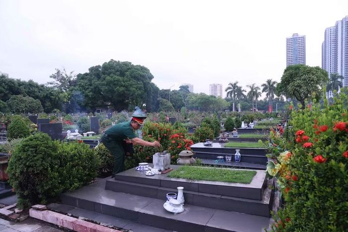Thắp hương trên phần mộ liệt sỹ tại Nghĩa trang Mai Dịch (phường Phú Diễn). (Ảnh: Văn Điệp/TTXVN) 