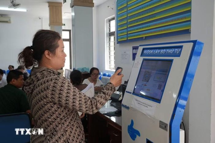 Người dân đến làm thủ tục hành chính tại Trung tâm Hành chính công xã Hòa Vang (Đà Nẵng) quét mã quét mã QR trên điện thoại thông minh. (Ảnh: Anh Dũng/TTXVN)