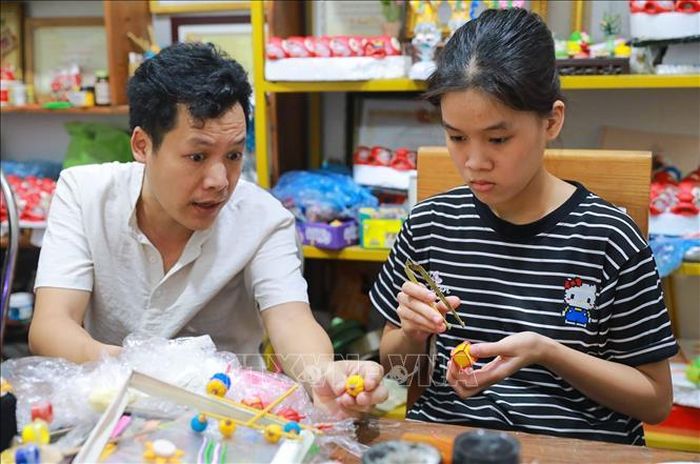Nghệ nhân Đặng Văn Hậu tận tình chỉ dạy, hướng dẫn cho các bạn trẻ.