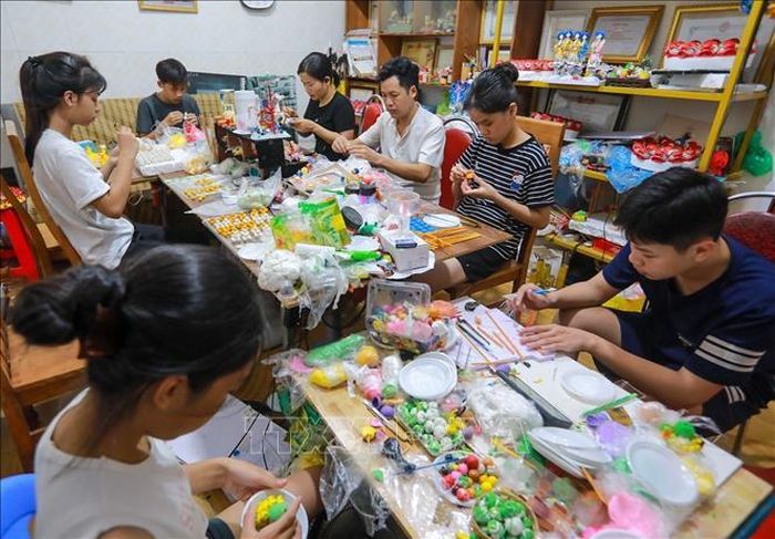 Nghệ nhân Đặng Văn Hậu tận tình chỉ dạy, hướng dẫn cho các bạn trẻ thực hiện tác phẩm tò he.
