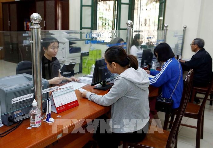 Nhân viên Bảo hiểm xã hội hướng dẫn người dân làm thủ tục tham gia Bảo hiểm xã hội. Ảnh: TTXVN