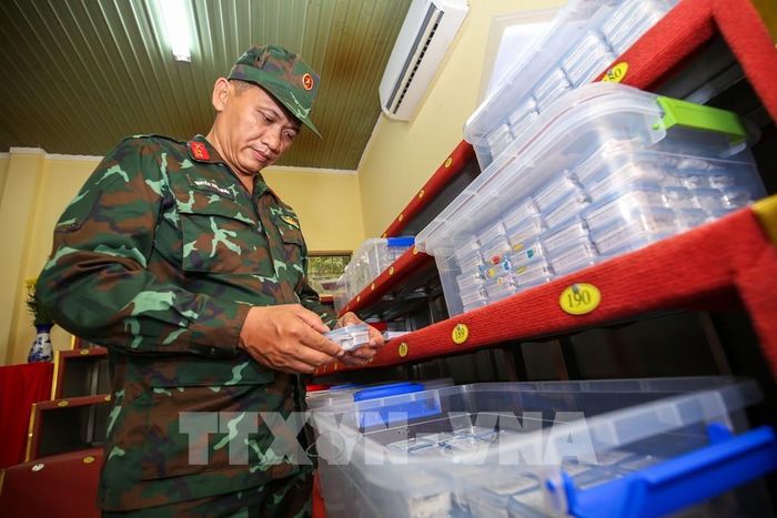 Trung tá Nguyễn Thiện Nghĩa kiểm tra, đối chiếu và tiếp nhận các mẫu hài cốt trước khi bàn giao cho đơn vị chuyên môn phục vụ giám định ADN. Ảnh: Giang Phương – TTXVN