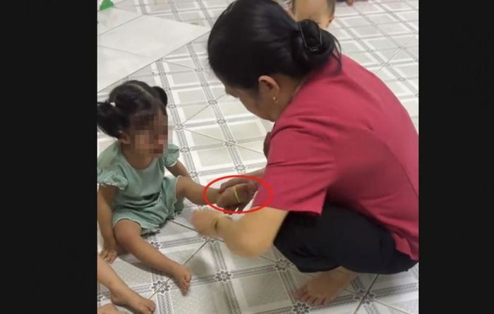 Hình ảnh bà Tâm có hành vi dùng dây thun bắn vào chân của cháu bé. Ảnh cắt từ clip.