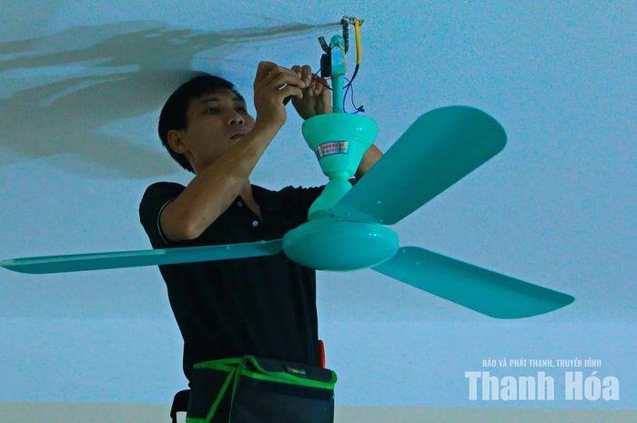 Công nhân lắp đặt quạt trần cho các phòng học.