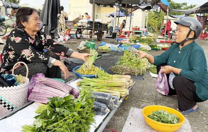 Bà Nguyễn Thị Sáng (bên trái) bán rau cho khách hàng. Ảnh: CẨM TÚ