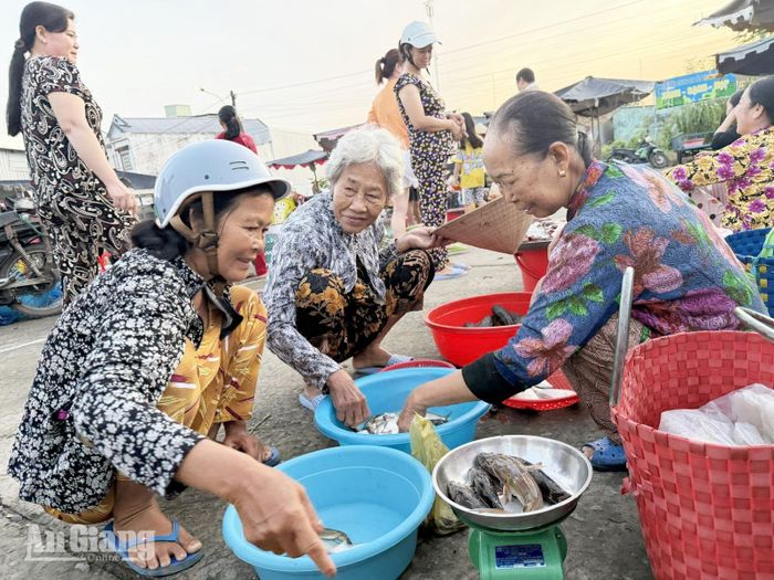 Tiểu thương tại “chợ ma” xã Ngọc Chúc bán cá cho khách hàng. Ảnh: CẨM TÚ
