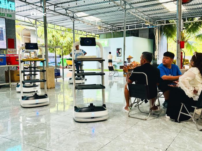 Du khách thích thú theo dõi và ghi lại khoảnh khắc robot phục vụ mang món đến bàn.