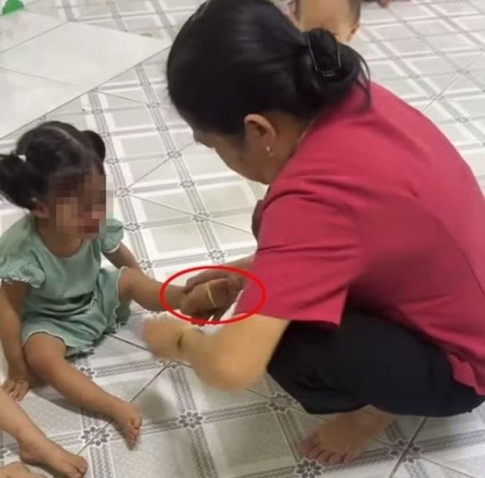 Khi bé gái không nín, người này dùng dây thun đeo vào chân bé và bắn làm bé đau (ảnh cắt trong video).