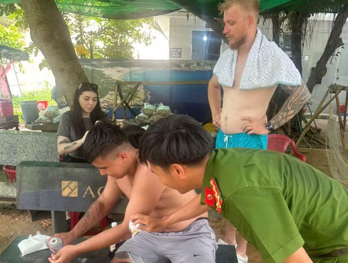 Cán bộ, chiến sĩ Công an xã Hòa Xuân hỗ trợ sơ cứu vết thương cho nhóm du khách nước ngoài sau khi được cứu hộ vào bờ.