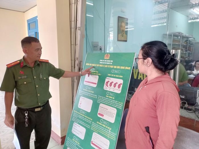 Thiếu tá Võ Văn Chiến, Phó trưởng Công an xã Diên Lâm hướng dẫn người dân thực hiện thủ tục đăng ký cấp phiếu lý lịch tư pháp qua ứng dụng VNeID. Ảnh: Hữu Toàn.