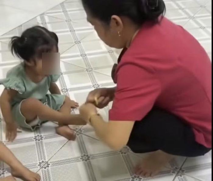  Nữ giáo viên dùng dây thun tác động vào chân trẻ. (Ảnh cắt từ clip). 