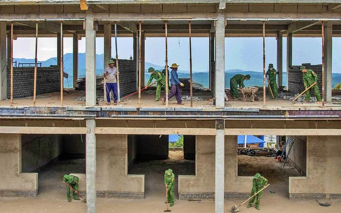 Bộ đội Biên phòng hỗ trợ lắp vận chuyển khung cửa để hoàn thiện khu nhà hành chính. Ảnh: Lê Văn Chương