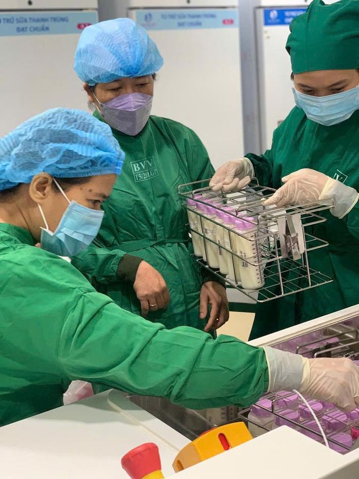 Nhân viên cho các bình sữa vào máy thanh trùng - Ảnh: T.T