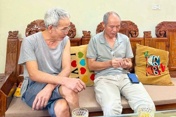 Ông Thắng (phải) cầm trên tay bức ảnh và trò chuyện tại nhà riêng của ông Chính. Ảnh: Gia đình cung cấp. 