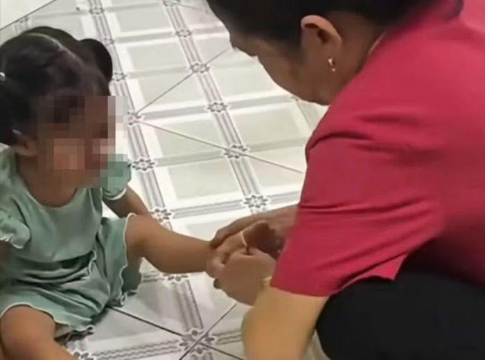 Hành vi cột dây thun vào chân để bật vào chân trẻ gây đau đớn. Ảnh cắt từ clip.