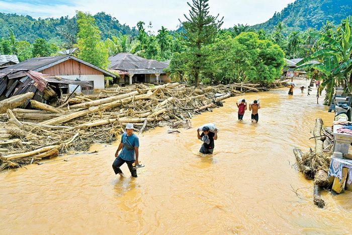 Người dân lội qua nước lũ sau trận lũ quét tại Tapanuli, Bắc Sumatra, Indonesia