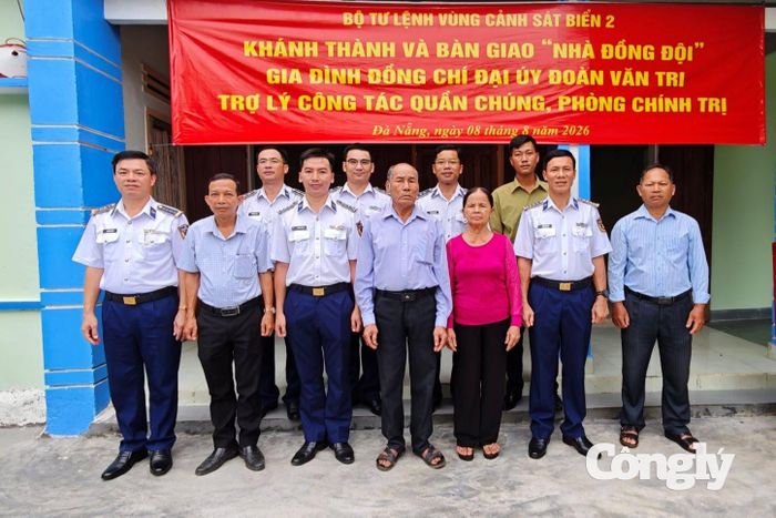 Đại diện Bộ Tư lệnh Vùng Cảnh sát biển 2 cùng lãnh đạo địa phương chụp ảnh lưu niệm với gia đình Đại úy Đoàn Văn Tri tại ngôi “Nhà đồng đội” vừa được bàn giao.