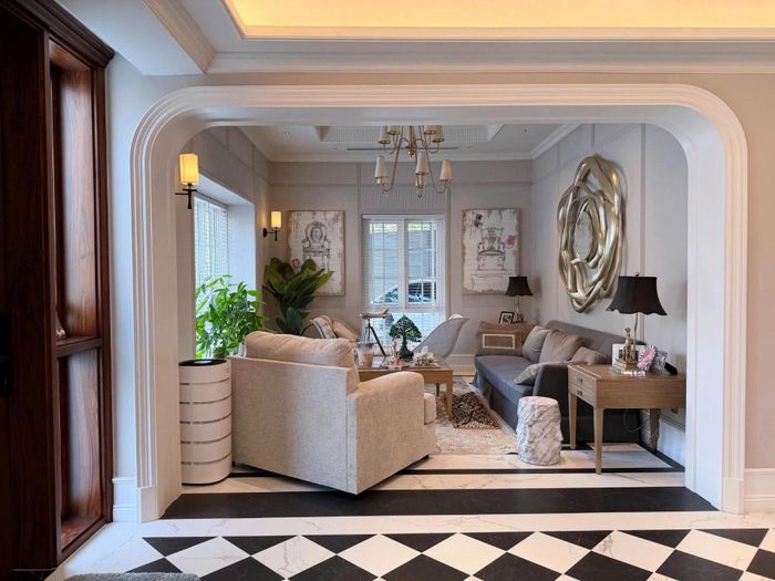 Biệt thự gồm 1 trệt, 1 lầu. Phòng khách được thiết kế theo phong cách tân cổ điển kết hợp các chi tiết hiện đại, tạo không gian sang trọng. Chiếc đèn chùm lớn với chao đèn hình gợn sóng là điểm nhấn tại khu vực sinh hoạt chung. 