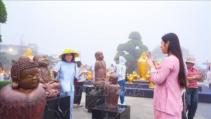 Du khách thích thú chụp ảnh lưu niệm với Bộ sưu tập “Phật Mình Chim” tại không gian Triển lãm “Kinh gốm – Thanh âm thế gian”. Ảnh: Minh Phú/TTXVN