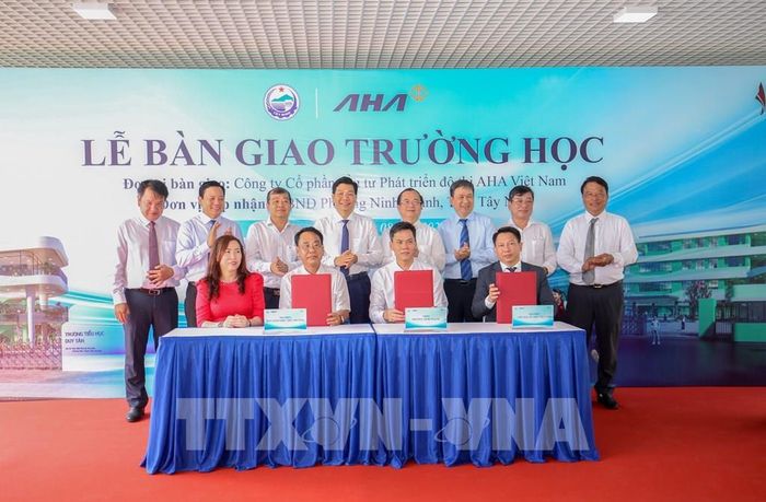 Đại diện các đơn vị thực hiện nghi thức ký kết bàn giao Trường Trung học cơ sở Nguyễn Thái Học và Trường Tiểu học Duy Tân. Ảnh: Giang Phương - TTXVN 