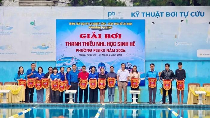 Ban tổ chức trao cờ lưu niệm cho các đoàn vận động viên tham dự Giải bơi thanh thiếu nhi, học sinh hè phường Pleiku năm 2026. Ảnh: M.C