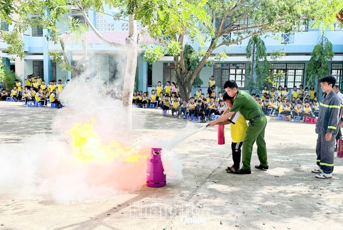 Lực lượng công an hướng dẫn thiếu nhi cách dập tắt ngọn lửa bằng bình chữa cháy.