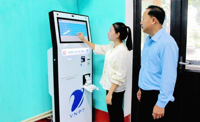 Cán bộ Trung tâm Phục vụ Hành chính công xã Vĩnh Thành hướng dẫn công dân lấy số tự động.