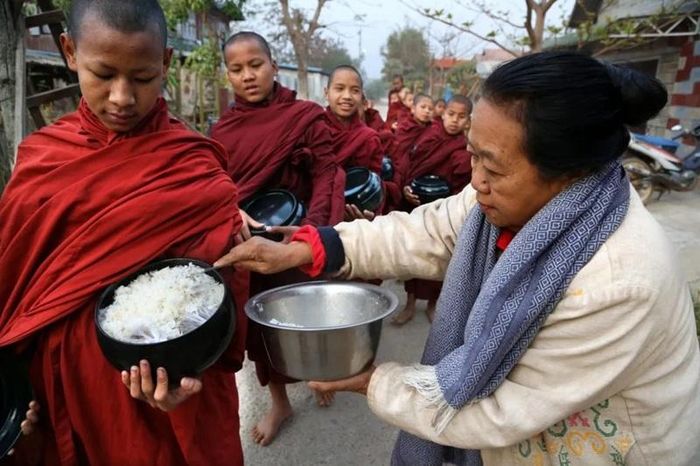Một nữ phật tử Myanmar cúng dường cơm cho các chú tiểu trong buổi khất thực hằng ngày. (Ảnh: Pascal Mannaerts/Alamy Stock Photo).