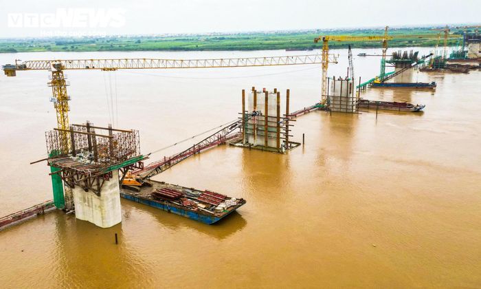 Trên công trường, các đơn vị thi công đang đồng thời triển khai nhiều hạng mục. Những trụ cầu giữa sông sau khi hoàn thành móng tiếp tục được thi công thân trụ, trong khi phần kết cấu phía trên cũng được triển khai song song nhằm rút ngắn thời gian thực hiện.