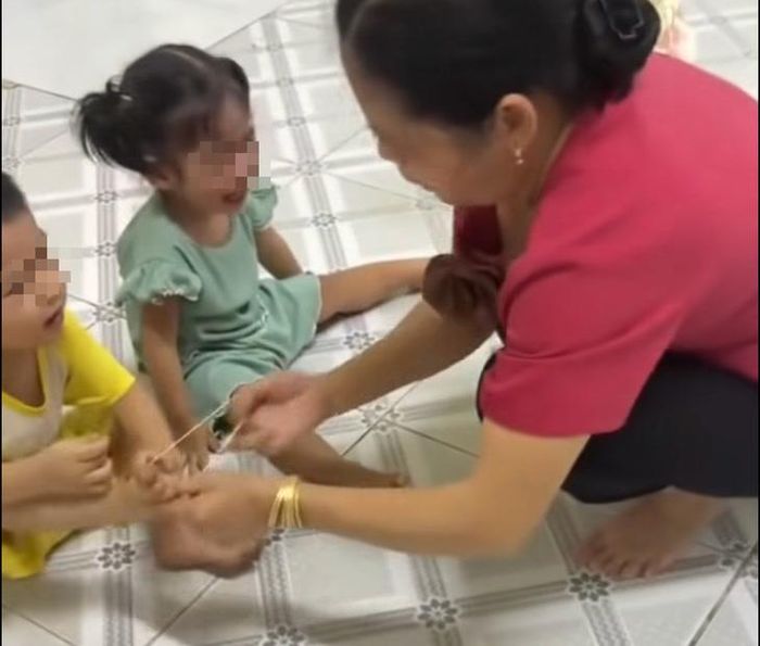 Đối tượng Triệu Thị Tâm đã dùng dây thun bắn vào chân trẻ. Ảnh: Cắt từ video.