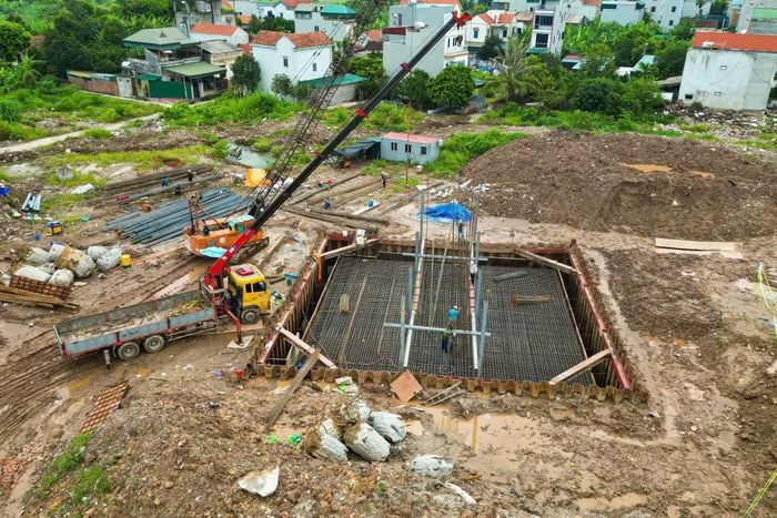 Tại phân đoạn bãi bồi sát bờ, hố móng cạn được đào sâu hàng mét. Xe cẩu tự hành túc trực trên miệng hố để hạ các lồng thép gia cường xuống vị trí móng.