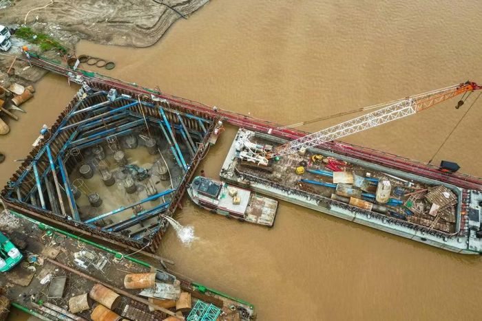 Một hố móng trụ giữa sông được bảo vệ bằng hệ khung cừ thép lục giác chịu lực. Bơm công suất cao xả nước liên tục ra lòng sông để công nhân làm sạch đầu cọc khoan nhồi trước khi đổ bê tông bệ trụ.