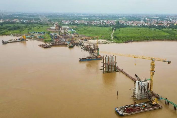 Xà lan nổi cùng cần trục tháp túc trực giữa dòng chảy xiết. Bê tông tươi được cung cấp trực tiếp từ trạm trộn nổi đỗ sát công trình để bảo đảm chất lượng và thời gian đóng kết.