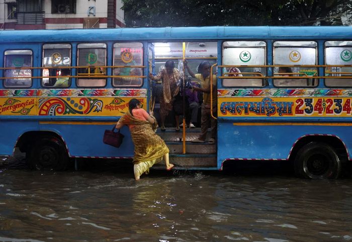 Một phụ nữ lên xe buýt trên con đường ngập nước sau những trận mưa lớn tại Kolkata, Ấn Độ, ngày 5/8. Trong ngày 6/8, Mumbai ghi nhận lượng mưa tới 222 mm trong 12 giờ. Sóng triều dâng cao tới 4,6 m khiến nước mưa không thể thoát ra biển, làm đường phố, đường sắt và các khu vực lân cận bị ngập úng.