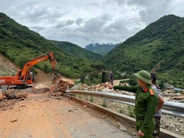 Lực lượng chức năng huy động máy móc khẩn trương dọn đất đá, khơi thông tuyến đường sau sạt lở