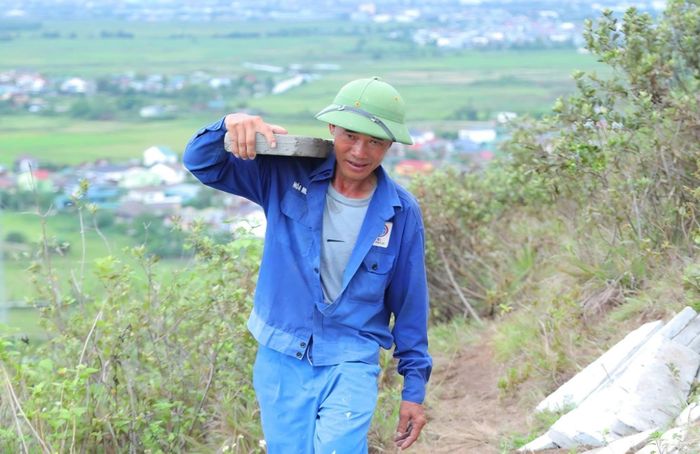 Những tấm bê tông nặng hơn 20kg lần lượt được đưa từ chân núi lên cao, vượt qua địa hình dốc để đến vị trí thi công.