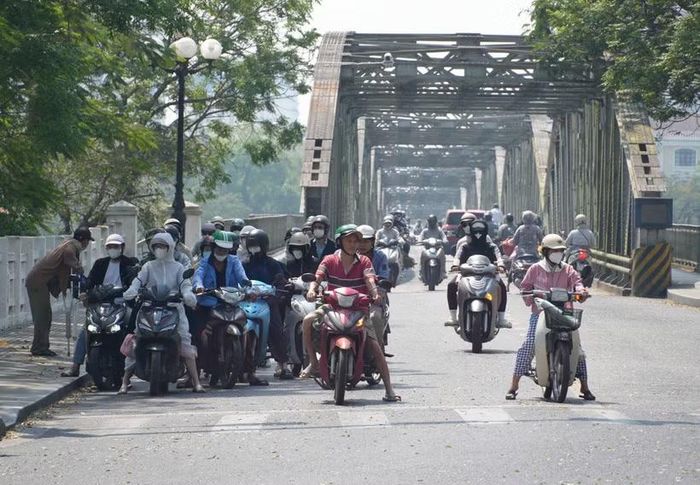 Người dân thành phố Huế mặc đồ bảo hộ chống nắng khi, di chuyển ở phía Bắc cầu Trường Tiền, phường Phú Xuân. (Ảnh: Nguyên Lý/TTXVN)