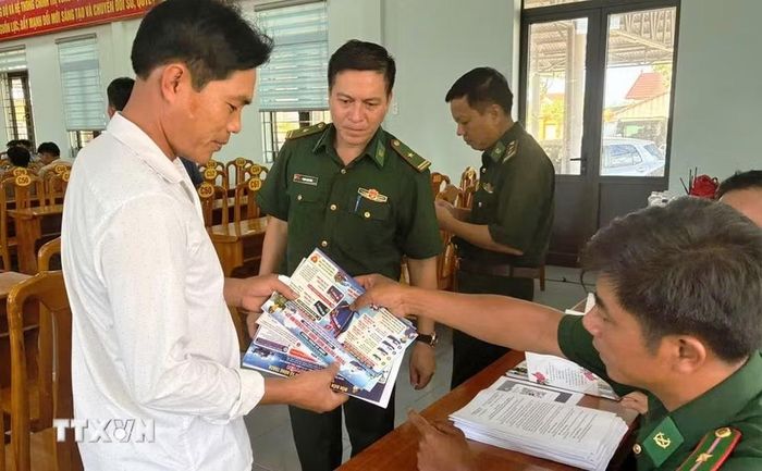 Cán bộ Đồn Biên phòng Lý Hòa cấp phát tờ rơi tuyên truyền, phổ biến những quy định mới của pháp luật. (Ảnh: Võ Dung/TTXVN)