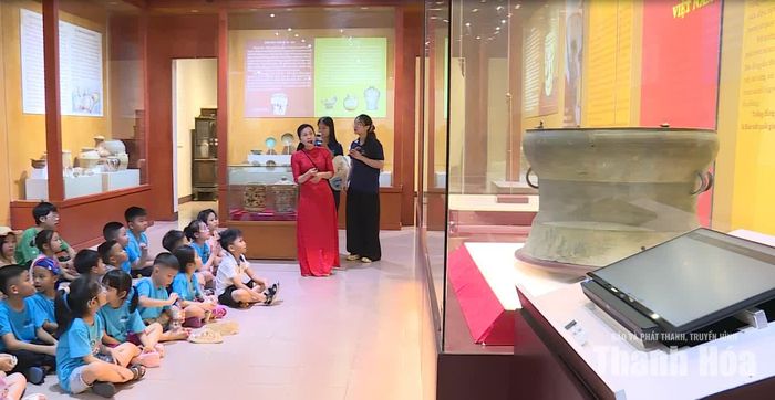 Thuyết minh viên giới thiệu cho các em học sinh về bảo vật quốc gia trống đồng Cẩm Giang.