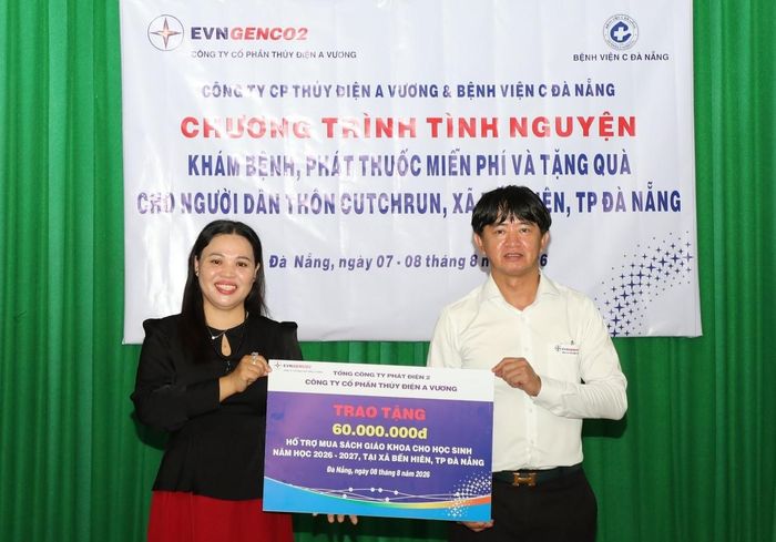 Ông Võ Trà Dũng, thành viên Hội đồng quản trị Công ty Cổ phần Thủy điện A Vương (bên phải) trao 60 triệu đồng hỗ trợ mua sách giáo khoa cho học sinh xã Bến Hiên. Ảnh: VĂN LÃM