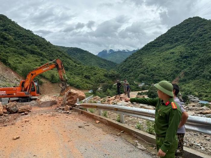 Lực lượng chức năng huy động máy móc khẩn trương dọn đất đá, khơi thông tuyến đường sau sạt lở. ẢNH: M.T