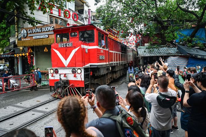 Du khách quốc tế phấn khích khi thấy đoàn tàu chạy sát con phố nhỏ ở Hà Nội, tháng 7/2025. Ảnh: Châu Sa.