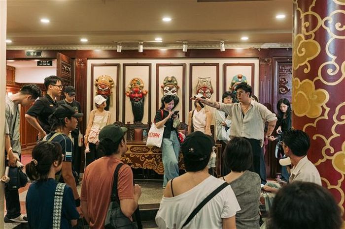 Anh Lê Duy Trung, founder của Gu Hanoi đang giải thích một số động tác Tuồng cho nhóm du khách đến xem vở diễn "Mộc Quế Anh dâng cây". Ảnh: Phạm Tuấn Anh - TTXVN