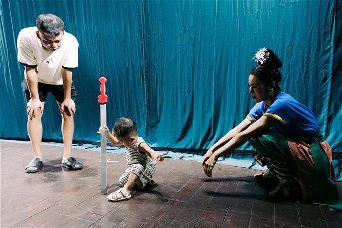 Một em nhỏ thích thú làm quen với đạo cụ biểu diễn dưới sự hướng dẫn của nghệ sĩ. Việc tạo điều kiện để nhiều lứa tuổi trực tiếp trải nghiệm là một cách mở rộng công chúng cho sân khấu truyền thống. Ảnh: Phạm Tuấn Anh - TTXVN