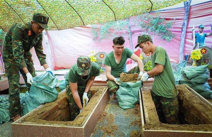 Việc đào, xúc đất được thực hiện từng bước, bảo đảm an toàn và giữ nguyên trạng tối đa khu vực phần mộ. Ảnh: Xuân Tư - TTXVN