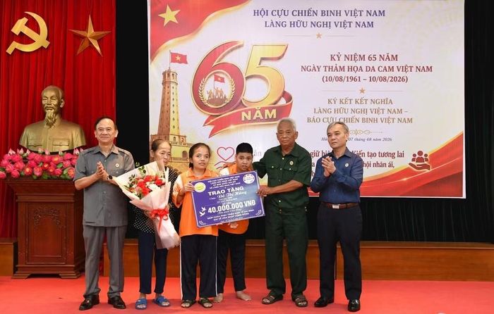 Đại diện Làng Hữu nghị Việt Nam trao tiền hỗ trợ cho nạn nhân da cam Đỗ Thị Hằng (thứ 3 từ trái qua) cùng gia đình.