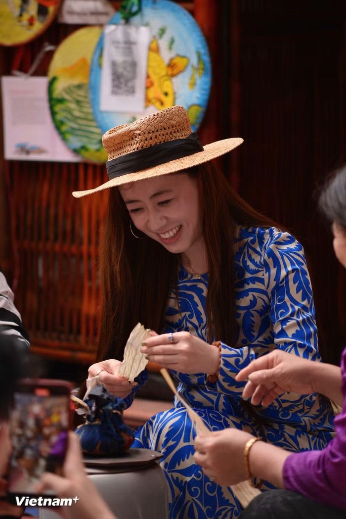 Nữ du khách Đài Loan (Trung Quốc) bày tỏ sự thích thú khi lần đầu trải nghiệm những công đoạn làm nón lá. (Ảnh: Mai Huyền/Vietnam+)