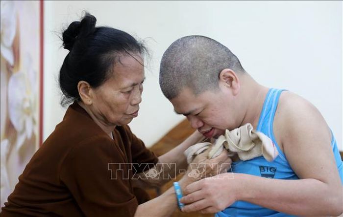 Dù tuổi đã cao nhưng bà Phạm Thị Lán (thôn Thượng Bái xã Diên Hà, tỉnh Hưng Yên) hàng ngày vẫn phải chăm sóc con trai bị ảnh hưởng bởi chất độc da cam/dioxin nằm liệt giường đã 41 năm nay. Ảnh: Thế Duyệt/TTXVN