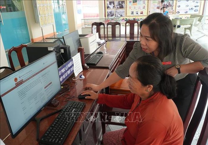 Cán bộ, công chức ở cơ sở hướng dẫn người dân làm thủ tục hành chính trực tuyến.