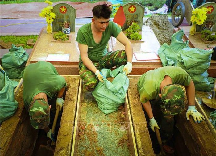 Các chiến sĩ cẩn trọng trong việc khai quật mộ liệt sĩ tại Nghĩa trang. Ảnh: Xuân Tư/TTXVN